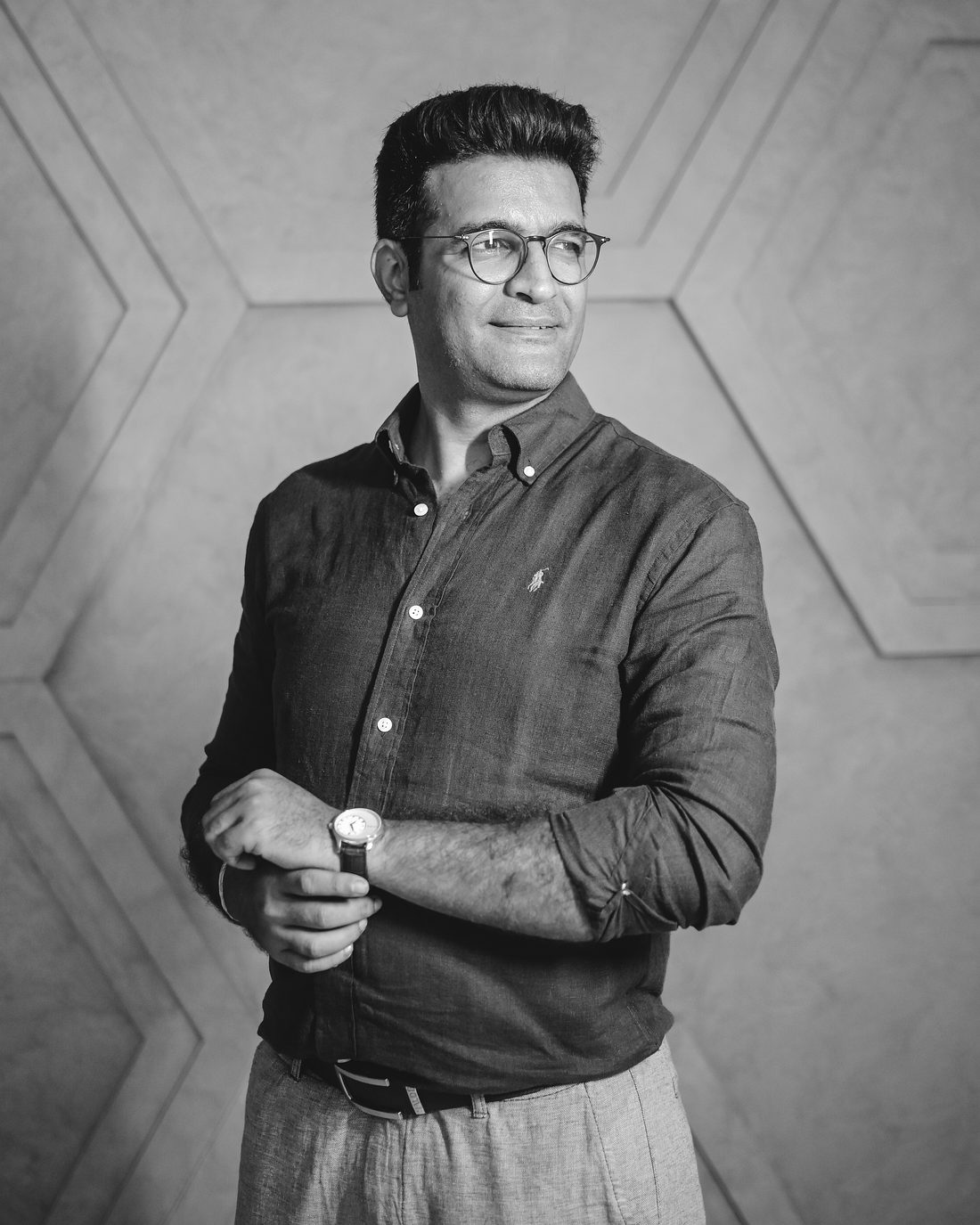 Mehul Dedhia standing, looking off camera, hands resting at his watch